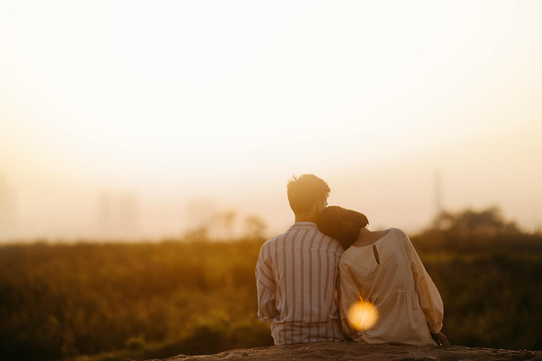 a couple watching a sunset while cuddling. 